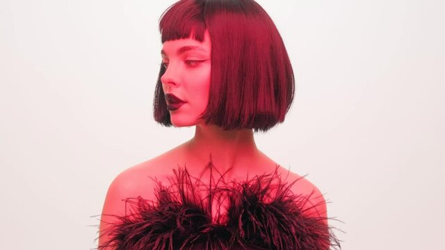 Portrait of a girl in red light with black lips and a wig on a white background in the studio. Woman in neon creative light.