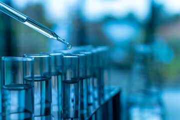 Concept of a chemical and scientific experiment. Closeup, copy space on right. Chemistry experiments in science labs. Drop chemical matter into a test tube. Many test tubes are placed on a white table