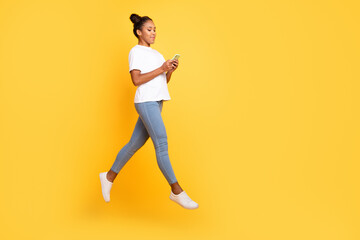 Fototapeta na wymiar Full body profile side photo of young african lady jumper use cellphone app repost isolated over yellow color background