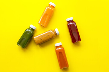 Fresh juices or cocktails of fruits and vegetables in bottles on a yellow background. The concept...