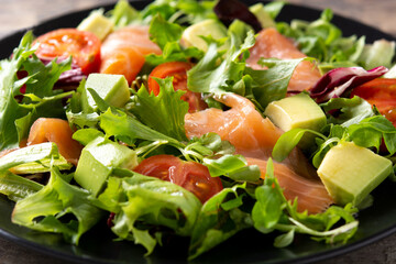 Salmon and avocado salad on rustic wooden table. Close up