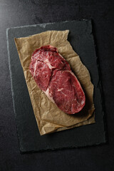 Entrecôte steak with fat marbling on a black background. Intermediate rib piece of beef, similar to a rib eye steak. Flat lay.