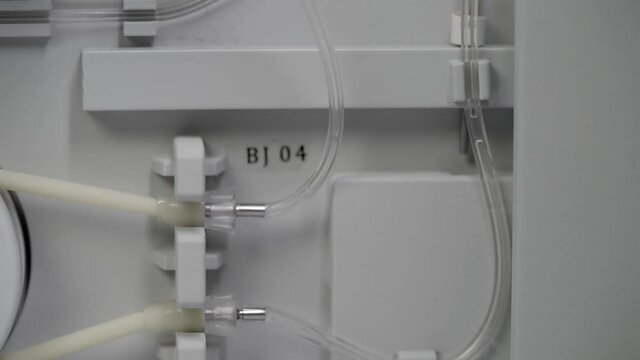 Fluid running through tubes in blood cbc machine. Close up, slomo tilt up