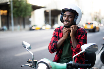 African man with scooter in the city. Young man riding a scooter...