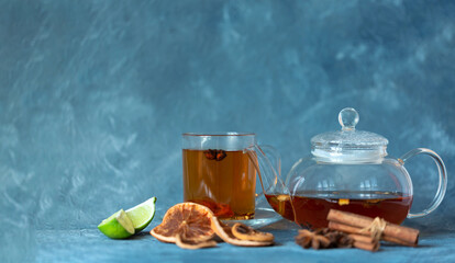 Hot black tea in a glass teapot and a cup of freshly brewed tea on a soft blue background.  Tea...