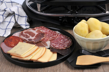 Assortiment de charcuterie et tranches de fromage pour faire une raclette