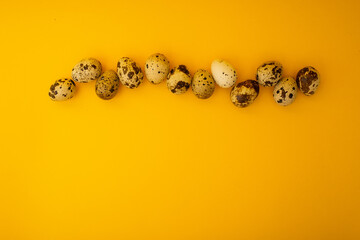 Small quail eggs lie on a yellow background, minimalism for advertising