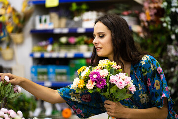 Beauty woman holding a bucket of flowers in a florist shop