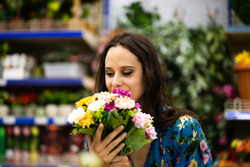 Woman smelling a bucket of flowers in a florist shop