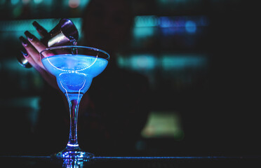 woman bartender hand at the bar or pub to prepare cocktail Blue Lagoon