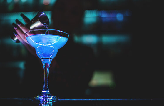 woman bartender hand at the bar or pub to prepare cocktail Blue Lagoon