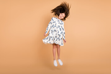 Full length body size view of attractive cheerful girl jumping throwing hair isolated on beige pastel color background