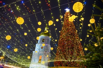 Fototapeten Christmas tree with bright festive illuminations and St. Sophia bell tower at the Sofiyska square in Kyiv, Ukraine © vlamus