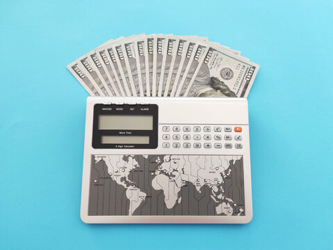 Calculator with one hundred dollars bills on a blue background