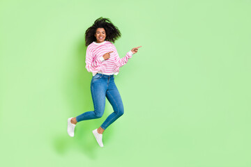 Fototapeta na wymiar Full length body size view of attractive cheerful lucky girl jumping showing copy space isolated on bright green color background