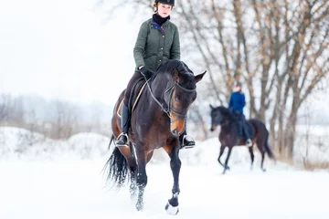 Outdoor kussens Young woman riding horse in winter park on the snow. © skumer