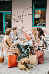 Company of senior woman having breakfast on a terrace of a street cafe after shopping
