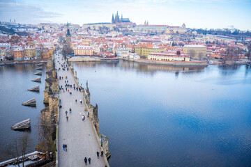 Fototapeta na wymiar People are walking on Charles bridge, whose rooftops are covered by snow, Prague in the winter