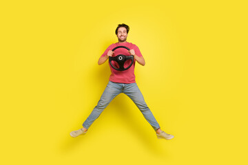 Fototapeta na wymiar Full size photo of nice beard young guy drive jump wear red t-shirt jeans footwear isolated on yellow background