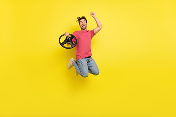 Full length photo of cool beard millennial guy drive hooray jump wear red t-shirt jeans shoes isolated on yellow background