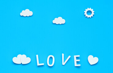 love, a word made of white letters. white hearts, clouds and sun on a blue background