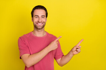 Photo of confident cheerful guy direct finger empty space novelty wear pink t-shirt isolated yellow color background