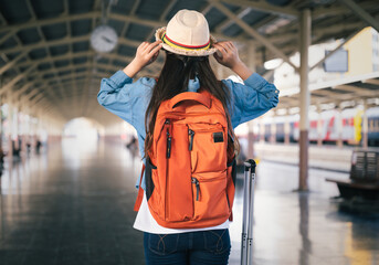Woman traveler tourist with bag and hat at train station