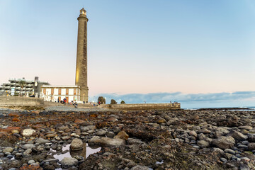 Fototapeta premium Lighthouse on rocky coast during sunset in Maspalomas, Gran Canaria, Spain