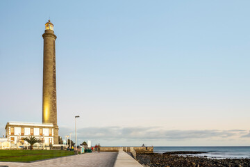 Fototapeta premium Lighthouse on rocky coast during sunset in Maspalomas, Gran Canaria, Spain
