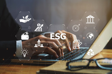 Businessman hand using a laptop with ESG icon on screen display, taking into account modern...