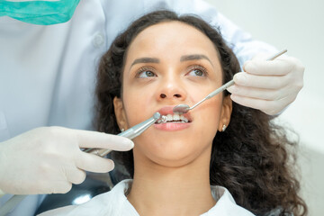 Dentist holding a tooth mirror and dental pick are performing dental exam on a patient in dental clinic