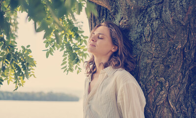 Beautiful young woman relaxing enjoying nature in the garden with closed eyes