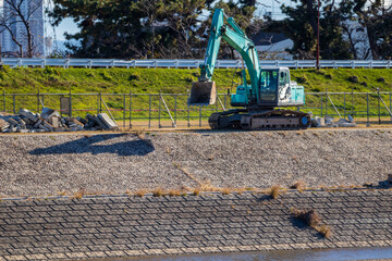 川岸の堤防の上で作業をする油圧ショベル