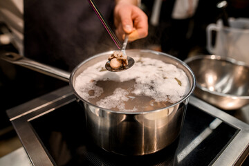small boiled octopus in a spoon over pot of water
