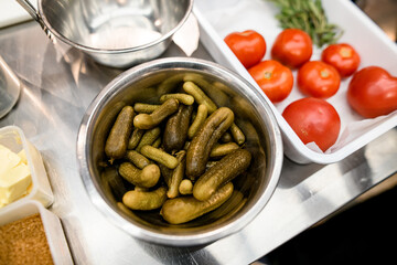 close-up view of green pickled cucumbers n metal bowl on the table