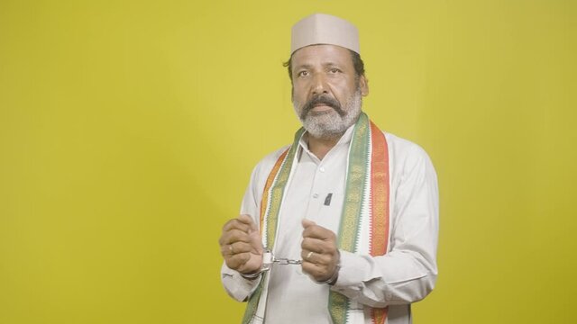Criminal Politician with Hand cuffs turns by looking camera on yellow background - concept of political crime, arrested political leader and trapped in politics