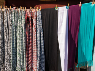 Colored shawls for sun protection are hanging for sale.