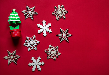 Christmas and New Year composition of beige wooden snowflakes and wooden fir tree model on a red fabric. Flat lay, copy space.