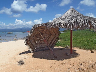 Fototapeta na wymiar Palm leaf umbrellas on the sandy beach.