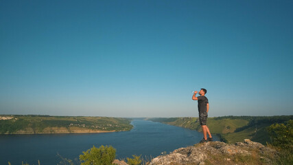 Fototapeta premium The man drinking water on a beautiful river background