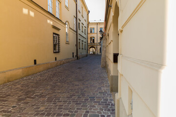 Tenement houses, facades and a paved street. Narrow streets of the old town in Krakow.