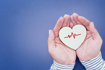 Fototapeta premium Man hands holding white paper heart shape and Heart cardiogram, heart health, world health day, world mental health day, medical and wellbeing.