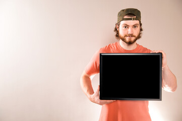 Young handsome bearded man showing black blank signboard, isolated on gray background