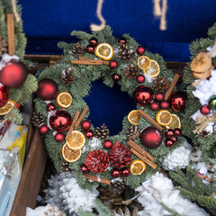 Christmas wreath of fir branches with decorations hanging on the wall of the house