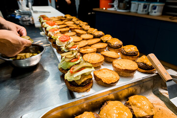 tray with many hamburger bun halves anointed with ketchup and mustard, served with cutlets and a slice of cheese