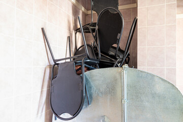 old broken cheap office chairs made of black eco-leather and metal are piled up in a corner of the...