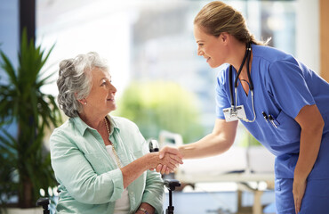Shot of a doctor shaking hands with a smiling senior woman sitting in a wheelchair