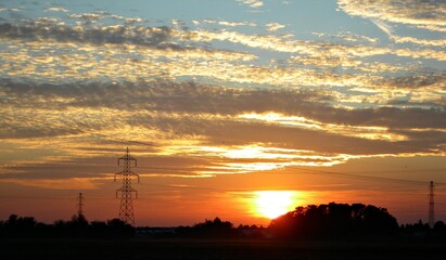 Fototapeta na wymiar Italy, Lombardy: Sunset with silhouettes of electricity pylons.