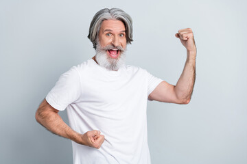 Photo of strong lucky man pensioner dressed white t-shirt rising fists smiling isolated grey color background