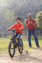 Fototapeta premium Grandfather teaching grandson riding bicycle at park 